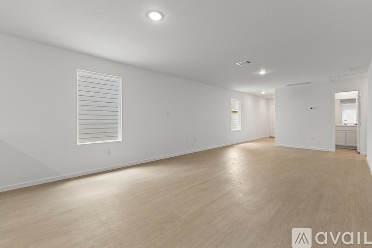 A spacious room with wooden flooring and white walls.