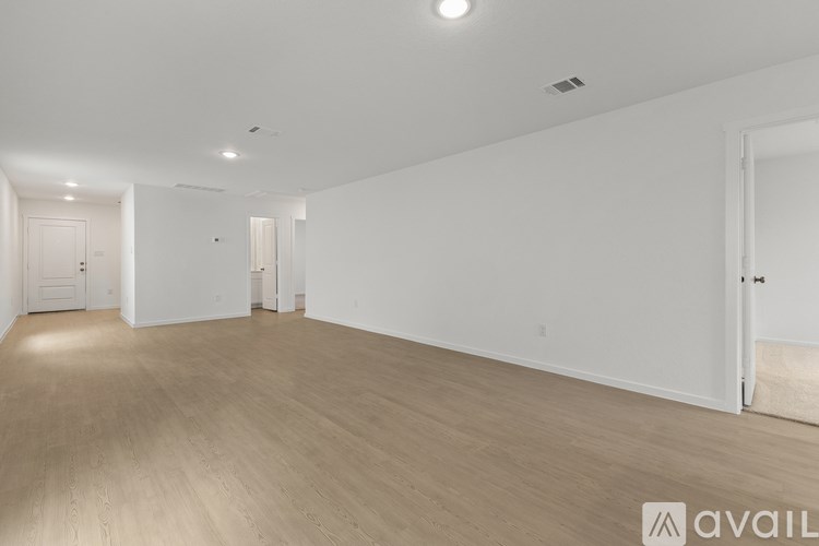A spacious room with wooden flooring and white walls.