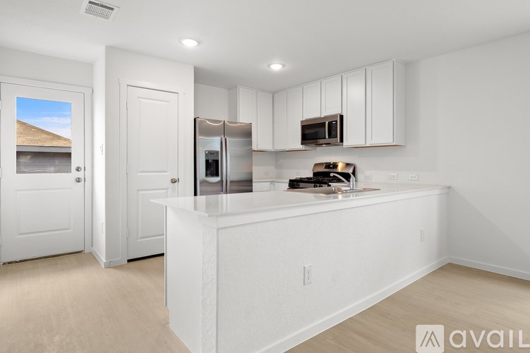 A kitchen with white cabinets and appliances, a countertop, and a window.