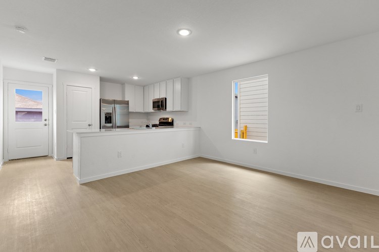 A spacious kitchen with white cabinets and a wooden floor.