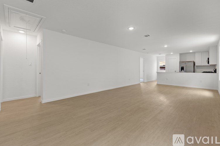 A spacious room with wooden flooring and white walls.