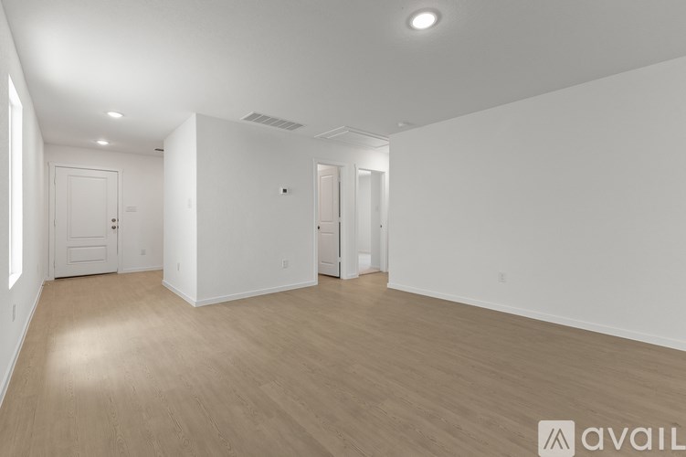 A spacious room with wooden flooring and white walls.