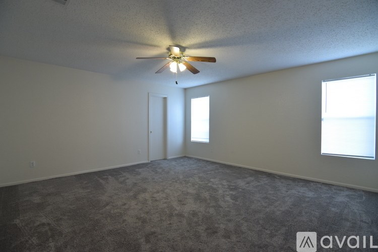A room with a ceiling fan and two windows.