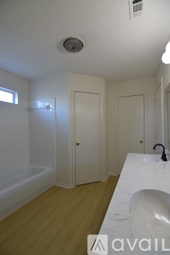 A bathroom with a tub, sink and mirror.