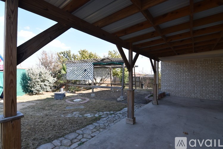 A patio area with a wooden pergola and a stone fire pit.