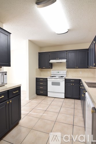 A kitchen with black cabinets and a white stove top oven.