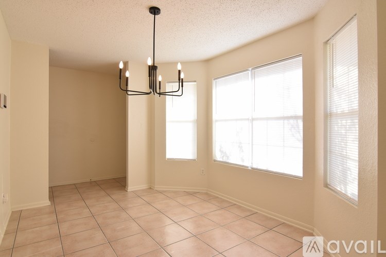 A room with a chandelier, tiled floor, and large windows.