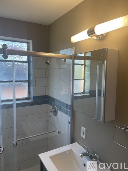 A bathroom with a white sink and a glass shower door.