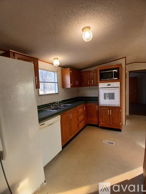 A white mobile home with a wooden fence and a green lawn in front.