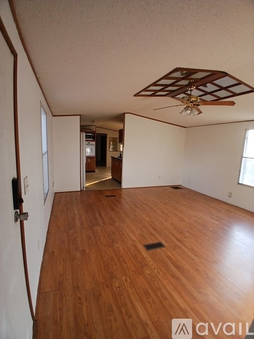 A white mobile home with a deck and a tree in the background.