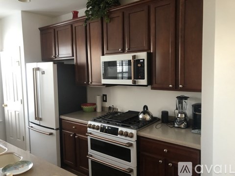 A kitchen with brown cabinets and a black refrigerator.