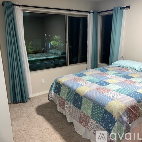 A bedroom with a bed and a window with curtains.
