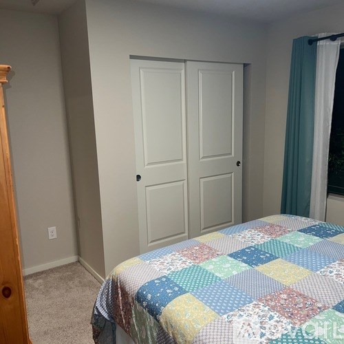 A bedroom with a bed, a closet, and a window.