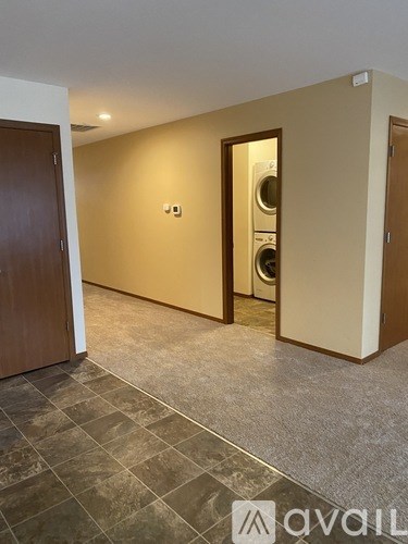 A room with two white doors, one of which is open, a carpeted floor, and a wooden dresser.
