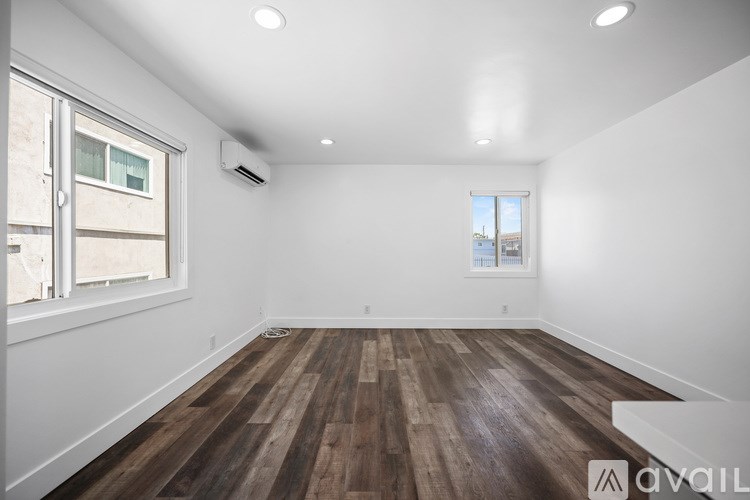 A spacious room with wooden flooring and a window.