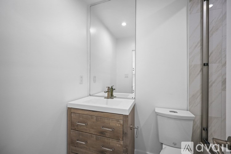A bathroom with a toilet, sink, and mirror.