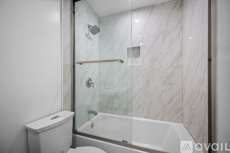 A white toilet sits next to a glass shower stall in a bathroom.