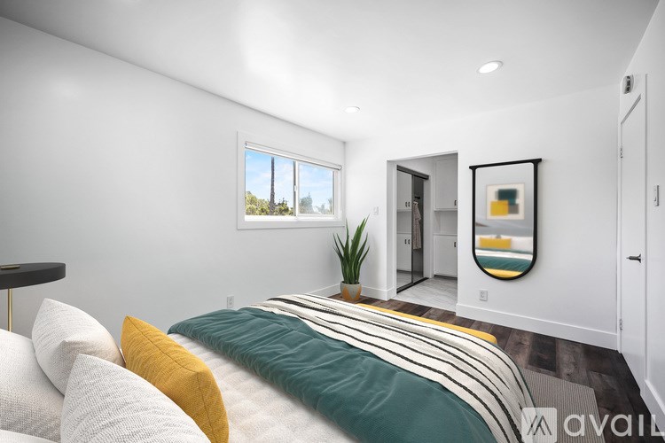 A bedroom with a bed, a mirror, and a painting on the wall.