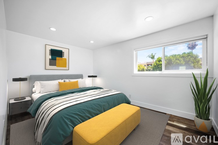 A bedroom with a bed, nightstand, and window.