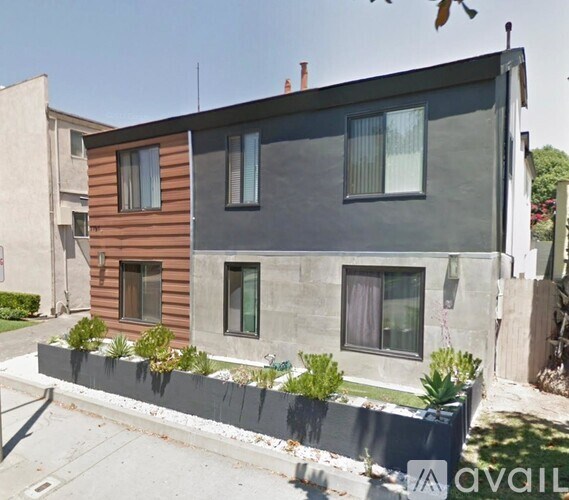 A modern two-story house with a grey front yard and a brown wooden exterior.