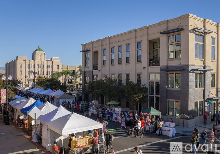 A busy street market is set up in front of a large building.