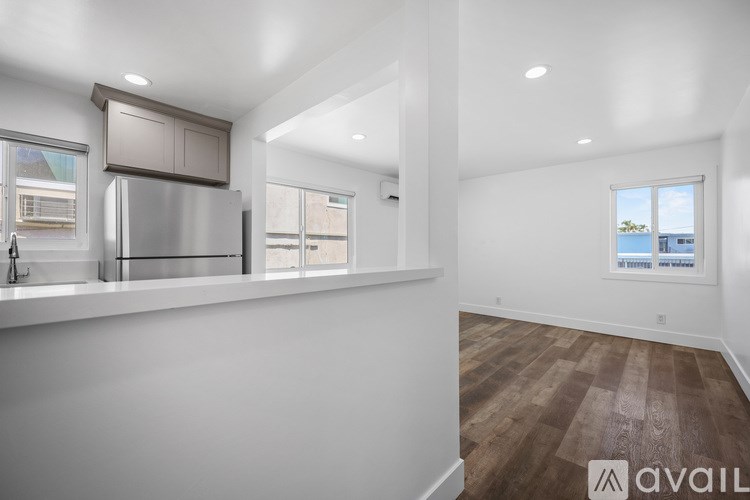 A kitchen with white walls and wooden floors is available for rent.