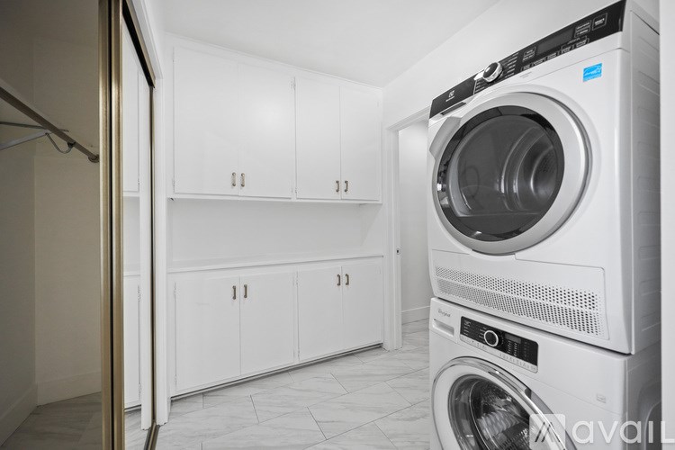 A white washing machine in a laundry room with white cabinets.