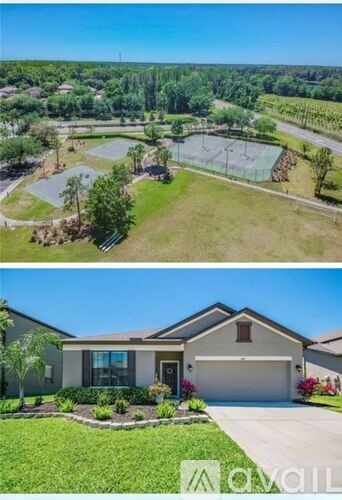 A house with a well-maintained lawn and a tennis court in the background.