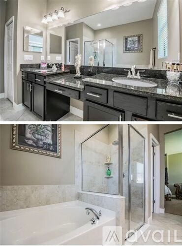 A bathroom with a black countertop and a white bathtub.