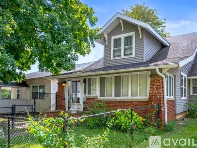 A house with a grey roof and a white fence is for sale.