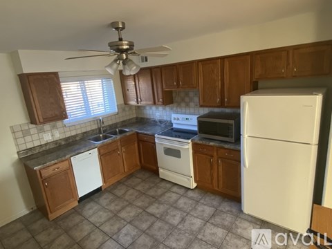 A kitchen with brown cabinets and a white fridge.