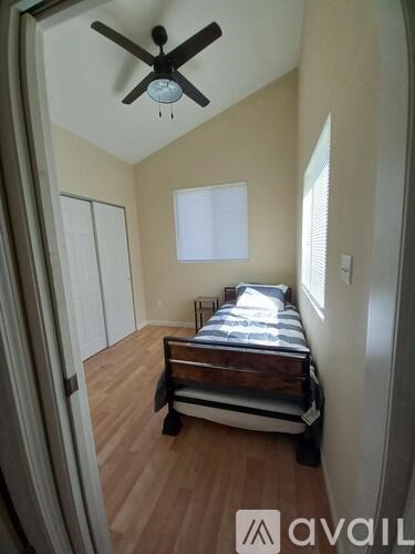 A bedroom with a bed, a ceiling fan, and a window.