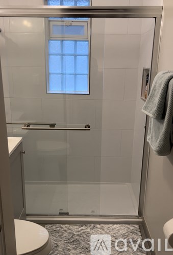 A bathroom with a glass shower door and a towel hanging on the door.
