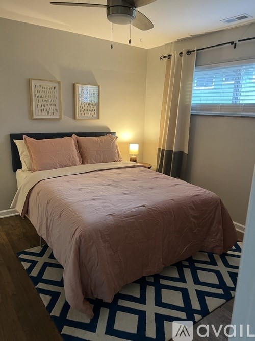 A bedroom with a bed, two pillows, a ceiling fan, and a window with blinds.