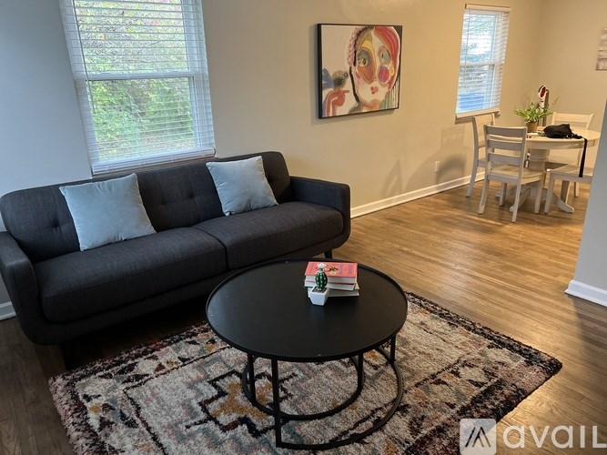 A living room with a grey couch, a black coffee table, and a painting on the wall.