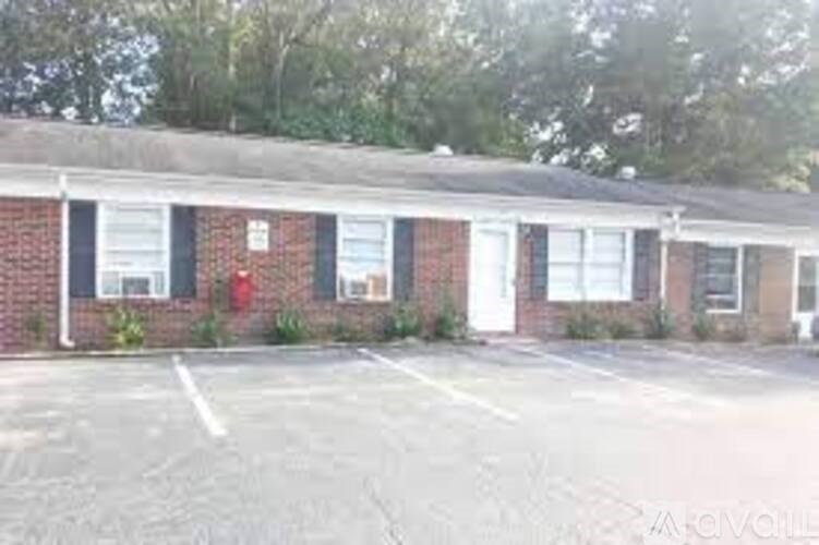 A small red brick building with a white door and windows.