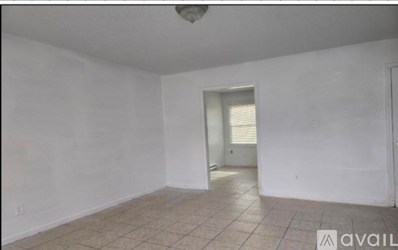 A room with a tiled floor and a doorway leading to another room.