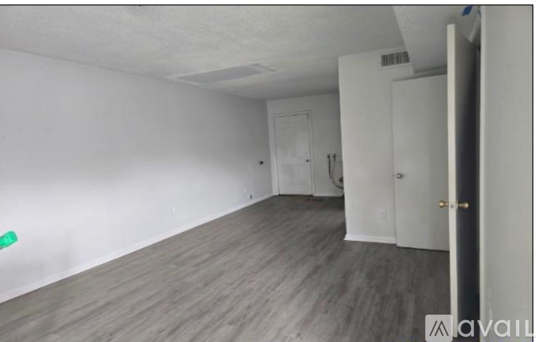 A room with white walls and a grey floor with a door on the right.