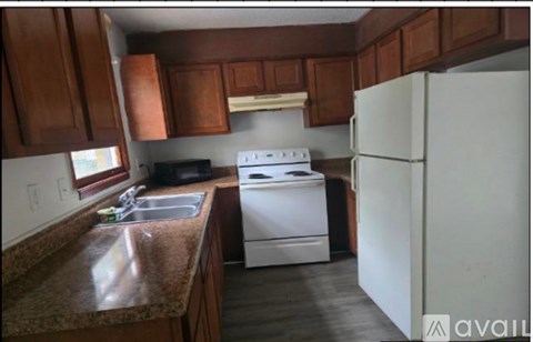 A kitchen with brown cabinets and a white stove and refrigerator.