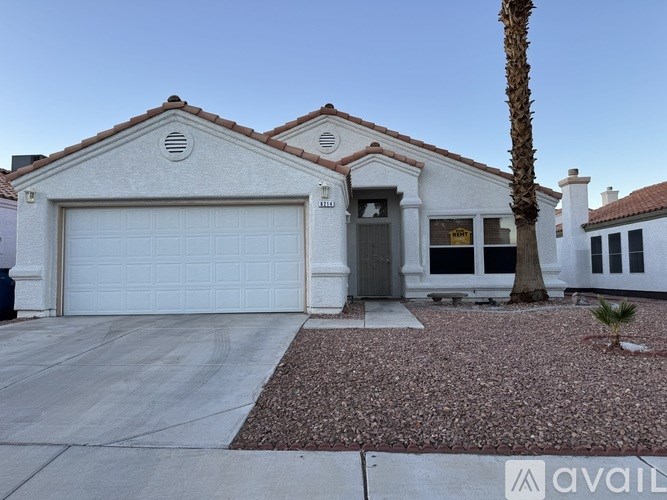 A house with a white garage door and a palm tree in front.