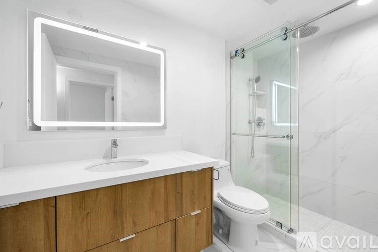 A modern bathroom with a white sink and a glass shower stall.