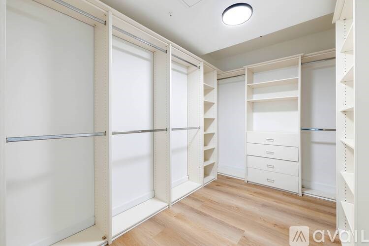 A white room with a wooden floor and a white ceiling with a light fixture.
