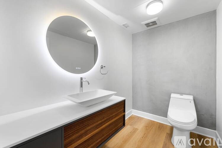 A bathroom with a round mirror, a sink, and a toilet.