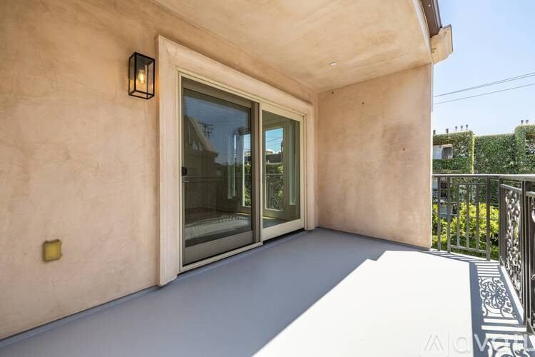 A balcony with a sliding glass door and a wall light.