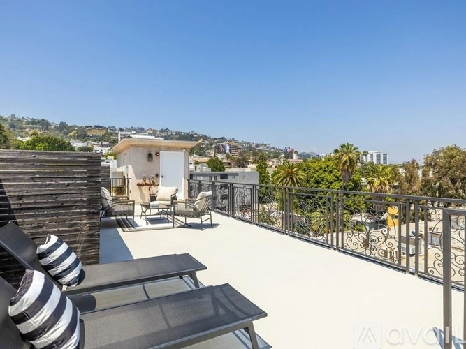 A balcony with a table and chairs overlooks a cityscape.