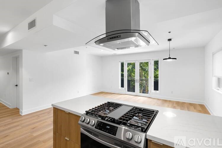 A modern kitchen with a stove top oven and a hood above it.