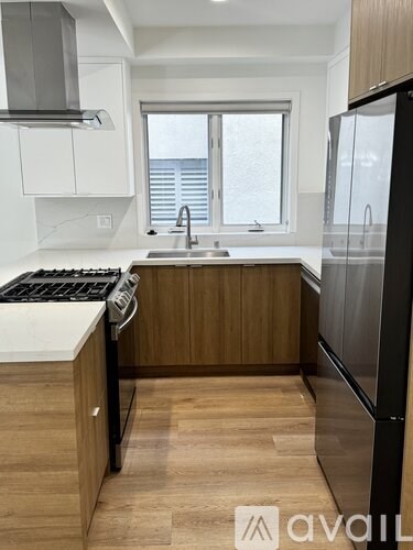 A kitchen with a black fridge and wooden cabinets.