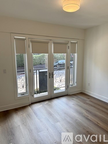 A room with a white door and a window with a view of a car and a fence.