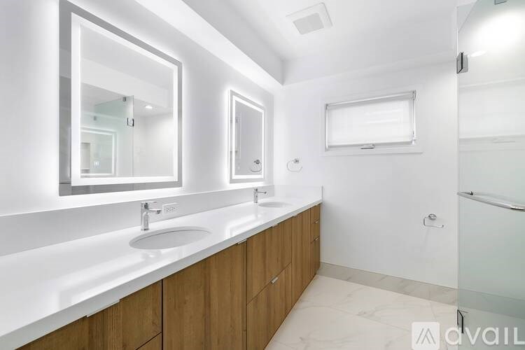 A modern bathroom with a white countertop and wooden cabinets.