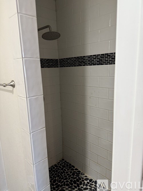 A white shower stall with a black and white tile floor.